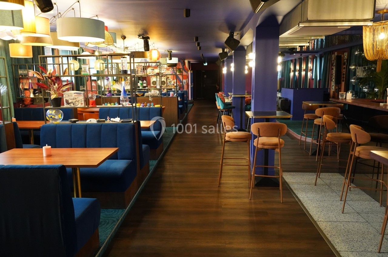Intérieur d'un restaurant moderne avec banquettes bleues, tables en bois et éclairage chaleureux.