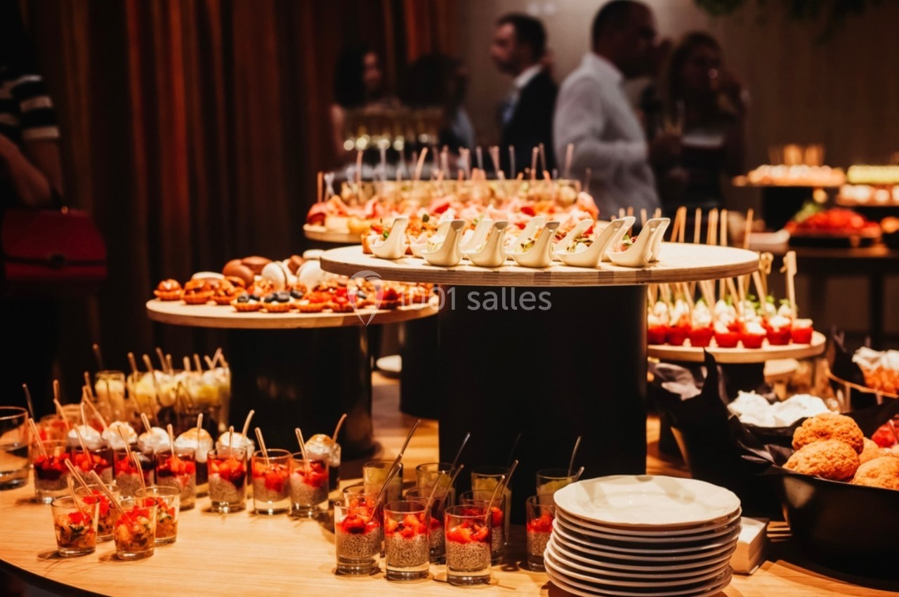 Buffet varié avec verrines, amuse-bouches et desserts présentés sur des plateaux dans un cadre élégant.