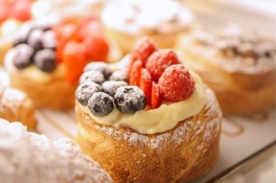 Bouchées apéritives élégantes surmontées de feuilles et de miettes croustillantes, disposées en rangées sur un plateau blanc.
