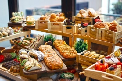 Bouchées apéritives élégantes surmontées de feuilles et de miettes croustillantes, disposées en rangées sur un plateau blanc.