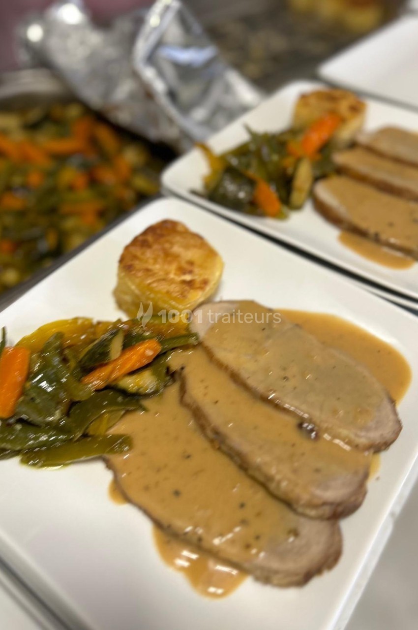 Assiette contenant des tranches de viande nappées de sauce, accompagnées de légumes sautés et d'une pomme de terre gratinée.