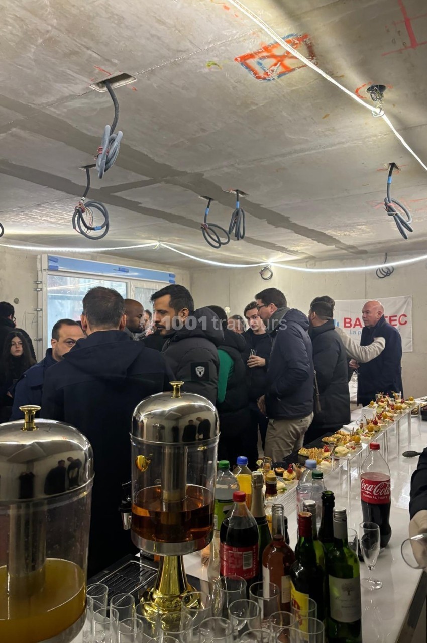 Des personnes rassemblées autour d'une table avec boissons et snacks dans un espace en construction.