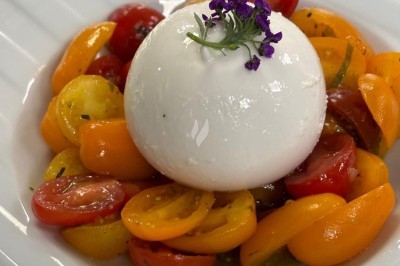 Miniature Traiteur Crosne (Essonne) - Aux Tulipes Traiteur #39 Assiette de burrata garnie de tomates cerises colorées et décorée d'une fleur violette sur une assiette blanche.