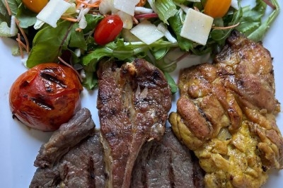 Miniature Traiteur Crosne (Essonne) - Aux Tulipes Traiteur #4 Assiette de burrata garnie de tomates cerises colorées et décorée d'une fleur violette sur une table blanche.