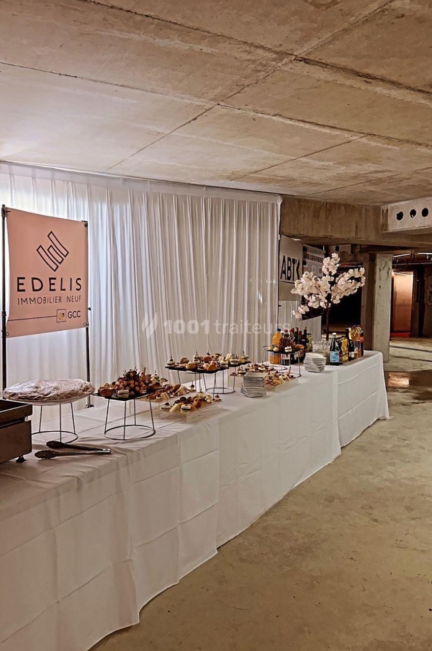 Table dressée avec des amuse-bouches variés, décorée sobrement, dans un espace intérieur au plafond en béton.