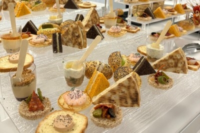 Miniature Traiteur Crosne (Essonne) - Aux Tulipes Traiteur #3 Assiette de burrata garnie de tomates cerises colorées et décorée d'une fleur violette sur une table blanche.