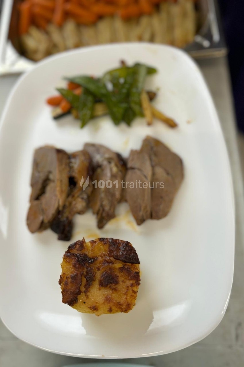 Assiette contenant des tranches de viande, un gratin doré et des légumes verts et colorés en accompagnement.