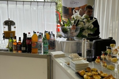 Miniature Traiteur Crosne (Essonne) - Aux Tulipes Traiteur #27 Assiette de burrata garnie de tomates cerises colorées et décorée d'une fleur violette sur une table blanche.