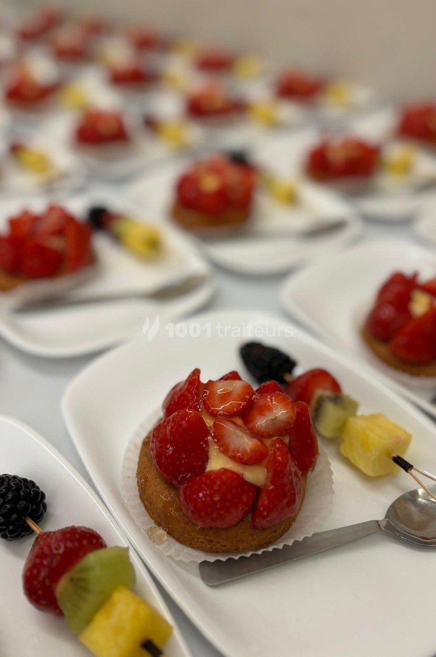 Assortiment de tartelettes aux fraises garnies de fruits frais, disposées sur des assiettes blanches avec des cuillères.