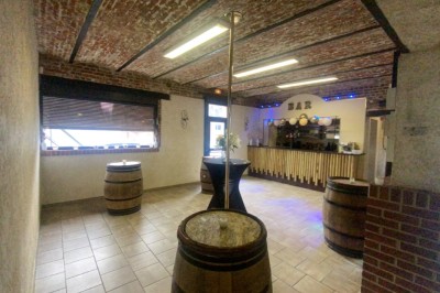 Miniature Location salle Maretz (Nord) - California #2 Salle avec un bar en bois, décorée de briques apparentes, tonneaux et une table haute ornée de fleurs blanches.