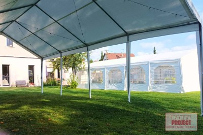 Structure blanche montée sur une pelouse, avec un grand chapiteau ouvert et un autre fermé en arrière-plan.