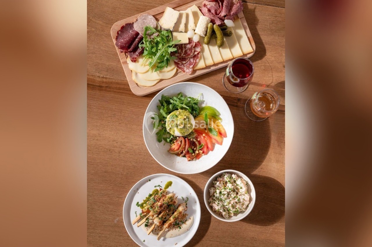 Assortiment de plats comprenant une planche de charcuterie et fromage, une salade, des brochettes et un bol de taboulé.