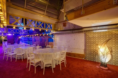 Salle décorée avec des tables rondes et chaises blanches, mur peint représentant une plage avec cabane et palmiers.
