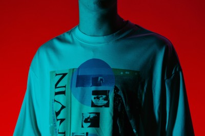 Un DJ mixe dans une ambiance de boîte de nuit avec des faisceaux lumineux et une foule floue en arrière-plan.
