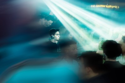 Miniature DJ Albigny-sur-Saône (Rhône) - Teebow #4 Un DJ mixe devant une foule dans une boîte de nuit éclairée par des lumières roses et des boules à facettes.