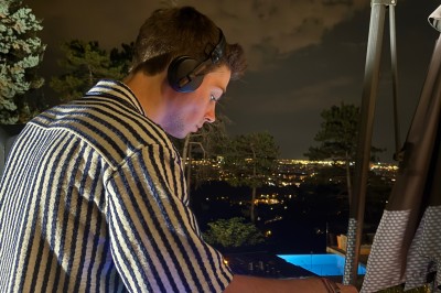 Miniature DJ Albigny-sur-Saône (Rhône) - Teebow #2 Un DJ mixe devant une foule dans une boîte de nuit éclairée par des lumières roses et des boules à facettes.