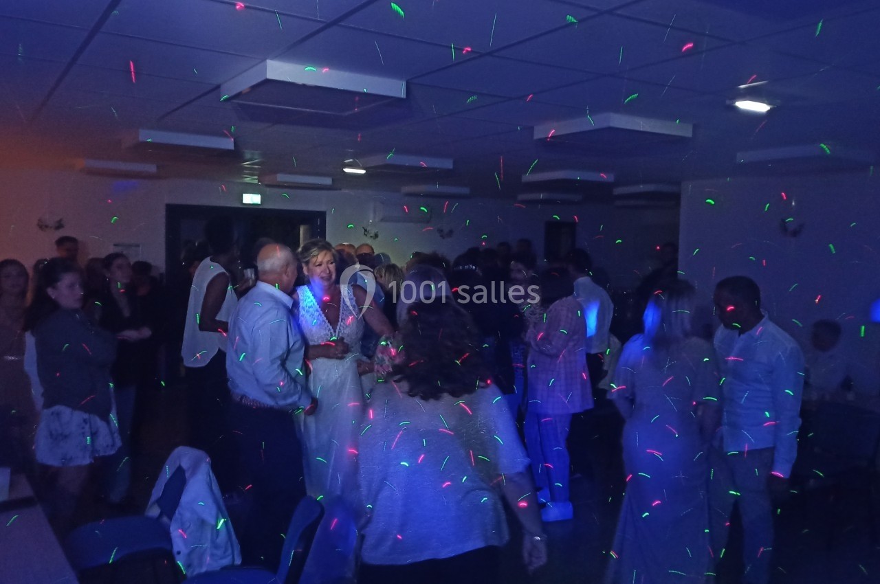 Groupe de personnes dans une salle éclairée par des lumières colorées lors d'une fête ou d'un événement.