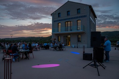 Miniature DJ Ventabren (Bouches-du-Rhône) - Provence Event #2 Un DJ en chemise rouge se tient derrière une table de mixage avec des lumières colorées en arrière-plan.