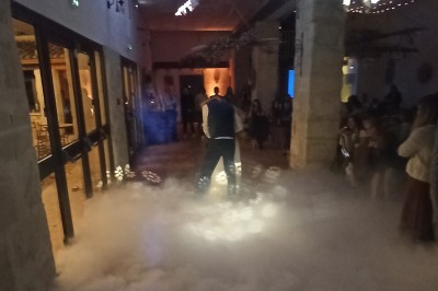 Miniature DJ Ventabren (Bouches-du-Rhône) - Provence Event #10 Un DJ en chemise rouge se tient derrière une table de mixage avec des lumières colorées en arrière-plan.