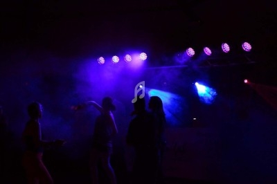 Miniature DJ Chignin (Savoie) - Anim'Fab #7 Un homme chante sur scène avec un micro, éclairé par une lumière rouge dans une ambiance sombre.