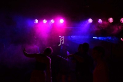 Miniature DJ Chignin (Savoie) - Anim'Fab #10 Un homme chante sur scène avec un micro, éclairé par une lumière rouge dans une ambiance sombre.