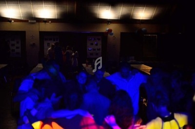 Miniature DJ Chignin (Savoie) - Anim'Fab #11 Un homme chante sur scène avec un micro, éclairé par une lumière rouge dans une ambiance sombre.