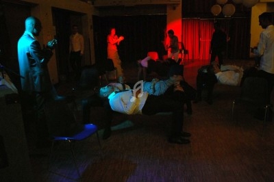 Miniature DJ Chignin (Savoie) - Anim'Fab #13 Un homme chante sur scène avec un micro, éclairé par une lumière rouge dans une ambiance sombre.