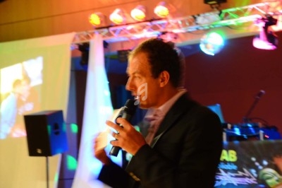 Miniature DJ Chignin (Savoie) - Anim'Fab #23 Un homme chante sur scène avec un micro, éclairé par une lumière rouge dans une ambiance sombre.