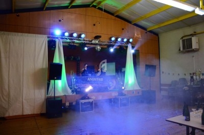 Miniature DJ Chignin (Savoie) - Anim'Fab #24 Un homme chante sur scène avec un micro, éclairé par une lumière rouge dans une ambiance sombre.