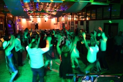 Miniature DJ Chignin (Savoie) - Anim'Fab #25 Un homme chante sur scène avec un micro, éclairé par une lumière rouge dans une ambiance sombre.