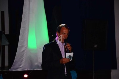 Miniature DJ Chignin (Savoie) - Anim'Fab #6 Un homme chante sur scène avec un micro, éclairé par une lumière rouge dans une ambiance sombre.