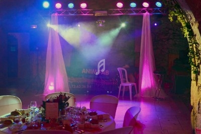 Miniature DJ Chignin (Savoie) - Anim'Fab #33 Un homme chante sur scène avec un micro, éclairé par une lumière rouge dans une ambiance sombre.