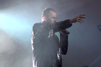 Miniature DJ Chignin (Savoie) - Anim'Fab #35 Un homme chante sur scène avec un micro, éclairé par une lumière rouge dans une ambiance sombre.