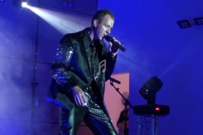 Miniature DJ Chignin (Savoie) - Anim'Fab #37 Un homme chante sur scène avec un micro, éclairé par une lumière rouge dans une ambiance sombre.