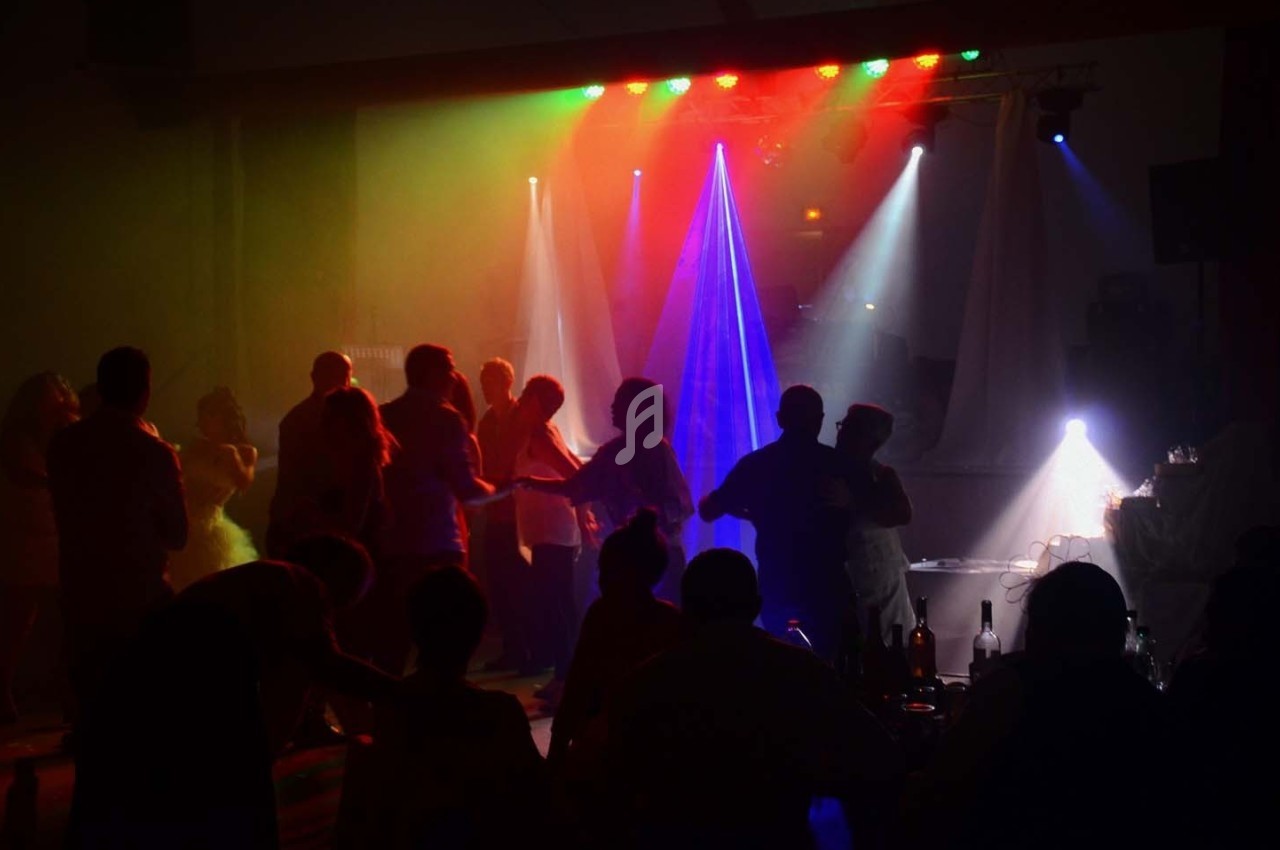 Des personnes dansent dans une salle sombre éclairée par des lumières colorées et des projecteurs.