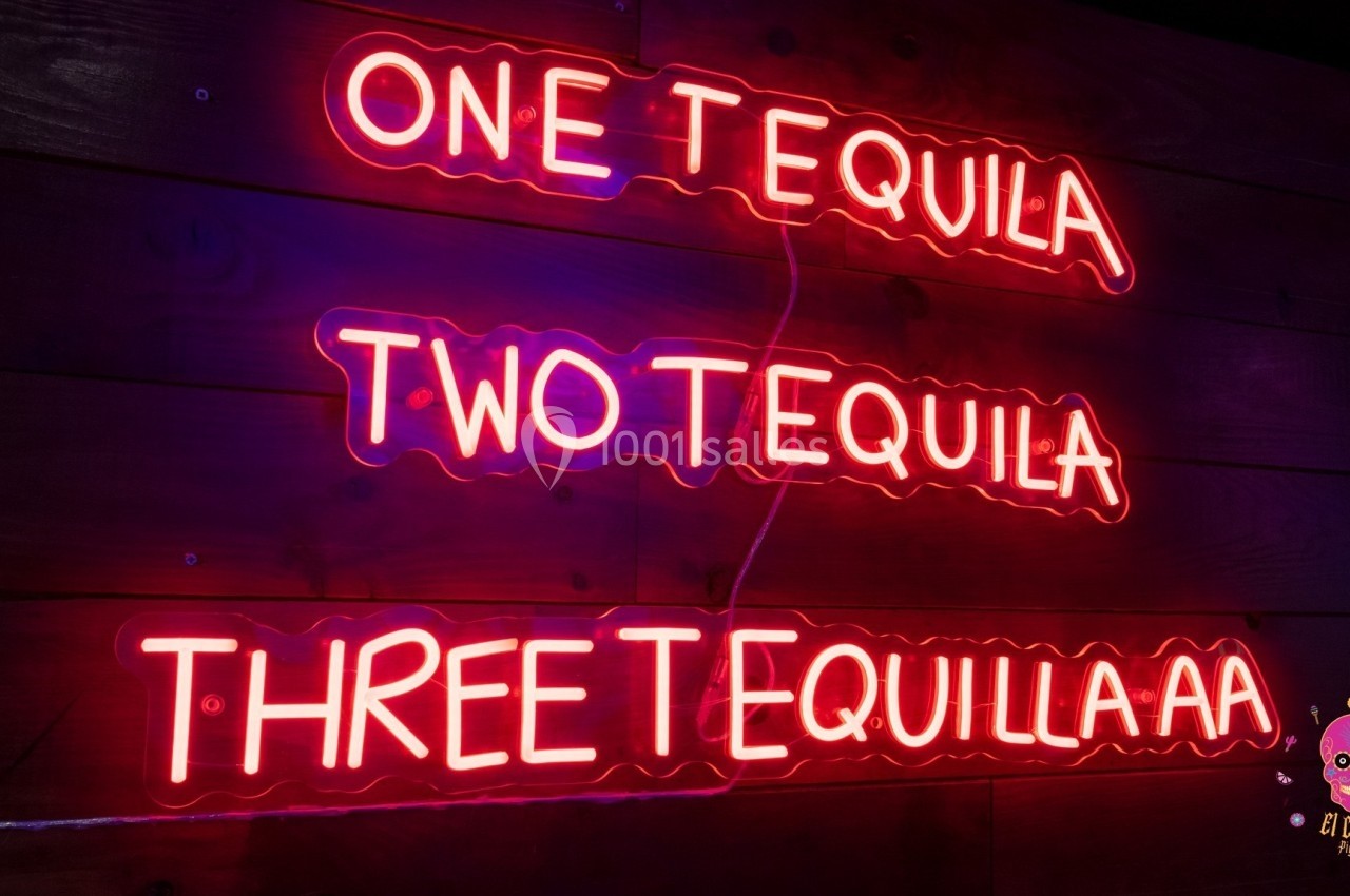 Texte néon rose sur fond sombre affichant ’One Tequila, Two Tequila, Three Tequila’ avec un logo de crâne coloré.