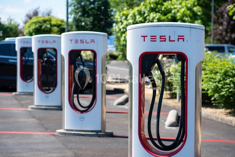 Location salle Nivelles (Brabant wallon) - Hôtel Nivelles Sud #21 Bornes de recharge électrique Tesla alignées dans un parking, entourées de verdure en arrière-plan.