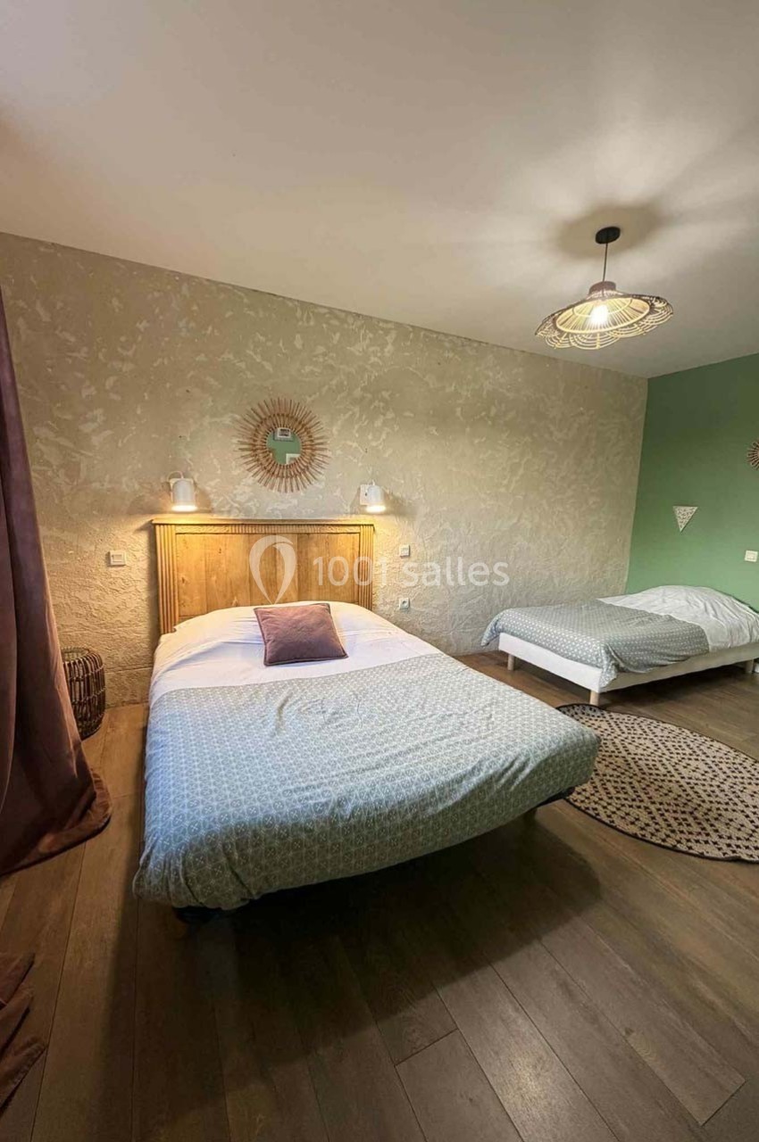 Chambre avec deux lits, parquet, mur texturé, décoration sobre et lumière naturelle filtrée par un rideau.