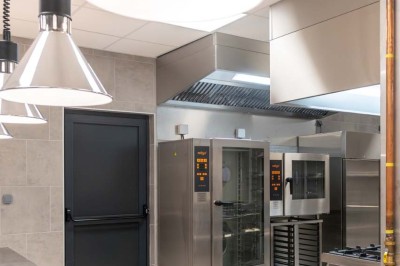 Miniature Location salle Saint-Laurent-Blangy (Pas-de-Calais) - Elegance Events #20 Cuisine professionnelle moderne avec équipements en inox, éclairage suspendu et fourneaux sous une hotte d'extraction.