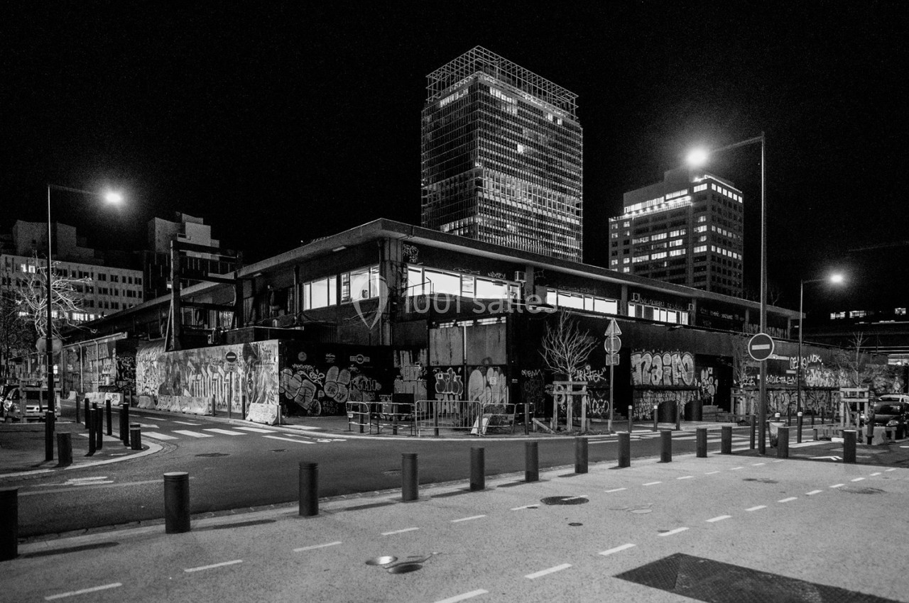 Bâtiment urbain recouvert de graffitis, entouré de rues désertes et éclairé par des lampadaires la nuit.