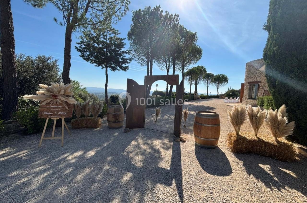 Entrée extérieure décorée avec des bottes de paille, des pampas, des tonneaux en bois et une vue sur des arbres et le…