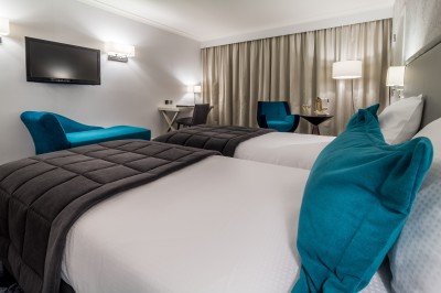 Femme allongée recevant un soin du visage avec un bandeau blanc, une personne nettoie sa peau avec des cotons.