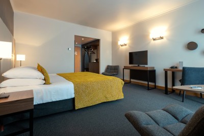 Femme allongée recevant un soin du visage avec un bandeau blanc, une personne nettoie sa peau avec des cotons.