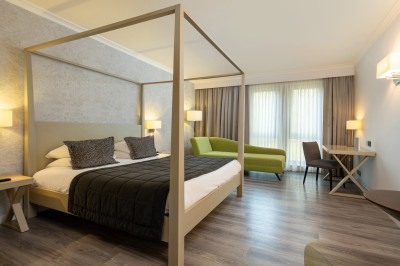 Femme allongée recevant un soin du visage avec un bandeau blanc, une personne nettoie sa peau avec des cotons.