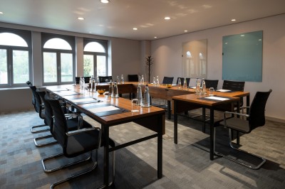 Femme allongée recevant un soin du visage avec un bandeau blanc, une personne nettoie sa peau avec des cotons.