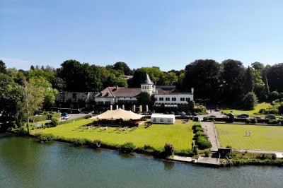 Femme allongée recevant un soin du visage avec un bandeau blanc, une personne nettoie sa peau avec des cotons.