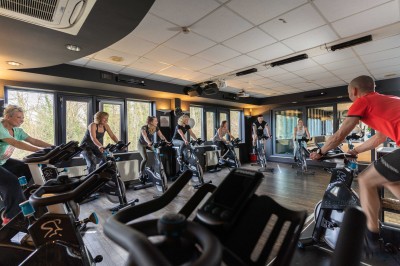 Femme allongée recevant un soin du visage avec un bandeau blanc, une personne nettoie sa peau avec des cotons.