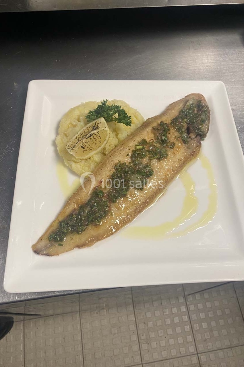 Filet de poisson grillé avec sauce verte, purée de pommes de terre, tranche de citron et persil, servi sur une assiette…