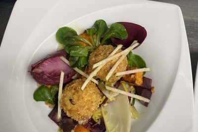 Miniature Location salle Rueil-Malmaison (Hauts-de-Seine) - Espace Laplace #21 Assiette de velouté orange garnie de croûtons dorés et de traits de crème blanche, servie sur une table en inox.