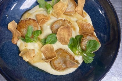 Miniature Location salle Rueil-Malmaison (Hauts-de-Seine) - Espace Laplace #24 Assiette de velouté orange garnie de croûtons dorés et de traits de crème blanche, servie sur une table en inox.